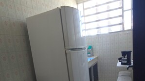 A compact kitchen with a refrigerator, a sink, and a window.