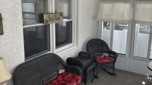 A covered porch with wicker furniture and a 'SeaShore' sign.