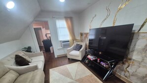 Ein Wohnzimmer mit einer Couch, einem Fernseher und einem gemusterten Teppich.
