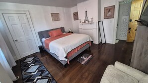 Ein Schlafzimmer mit einem Bett, einem Nachttisch, einem Spiegel, einer Tür und einem gemusterten Teppich.