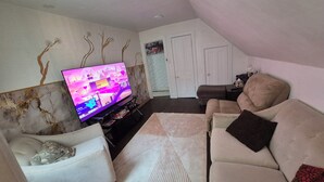 Ein Wohnzimmer mit Fernseher, Sofa und einem gemusterten Teppich.