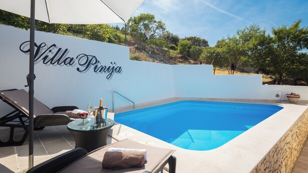 A poolside area with a lounge chair, a table with a towel, and a sign reading "Villa Pinja." - Villa with private pool, terrace and garden with fireplace (Nerezisca)