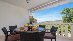 A balcony with a round table, wicker chairs, and a view of the landscape. - Villa with private pool, terrace and garden with fireplace (Nerezisca)