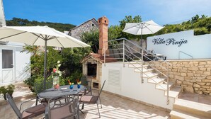 A patio area with a stone wall, outdoor seating, and a staircase leading to a villa named "Villa Pinja". - Villa with private pool, terrace and garden with fireplace (Nerezisca)