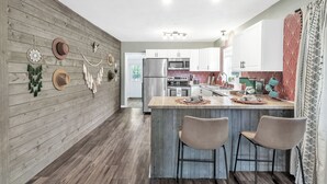 Eine moderne Küche mit Holzwänden, einer Kochinsel und Barhocker.