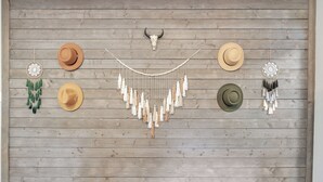 Eine Holzwand mit einem Schädel und vier hängenden Hüten.