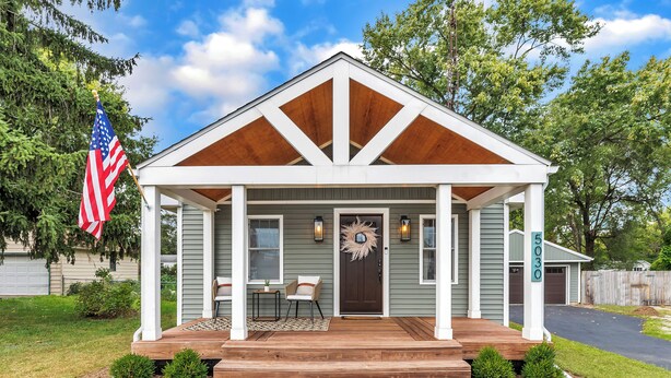 Ein eingeschossiges Haus mit Veranda, Garage und kleinem Vorgarten.