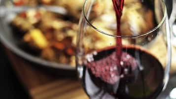 Una botella de vino vertiendo vino tinto en una copa.