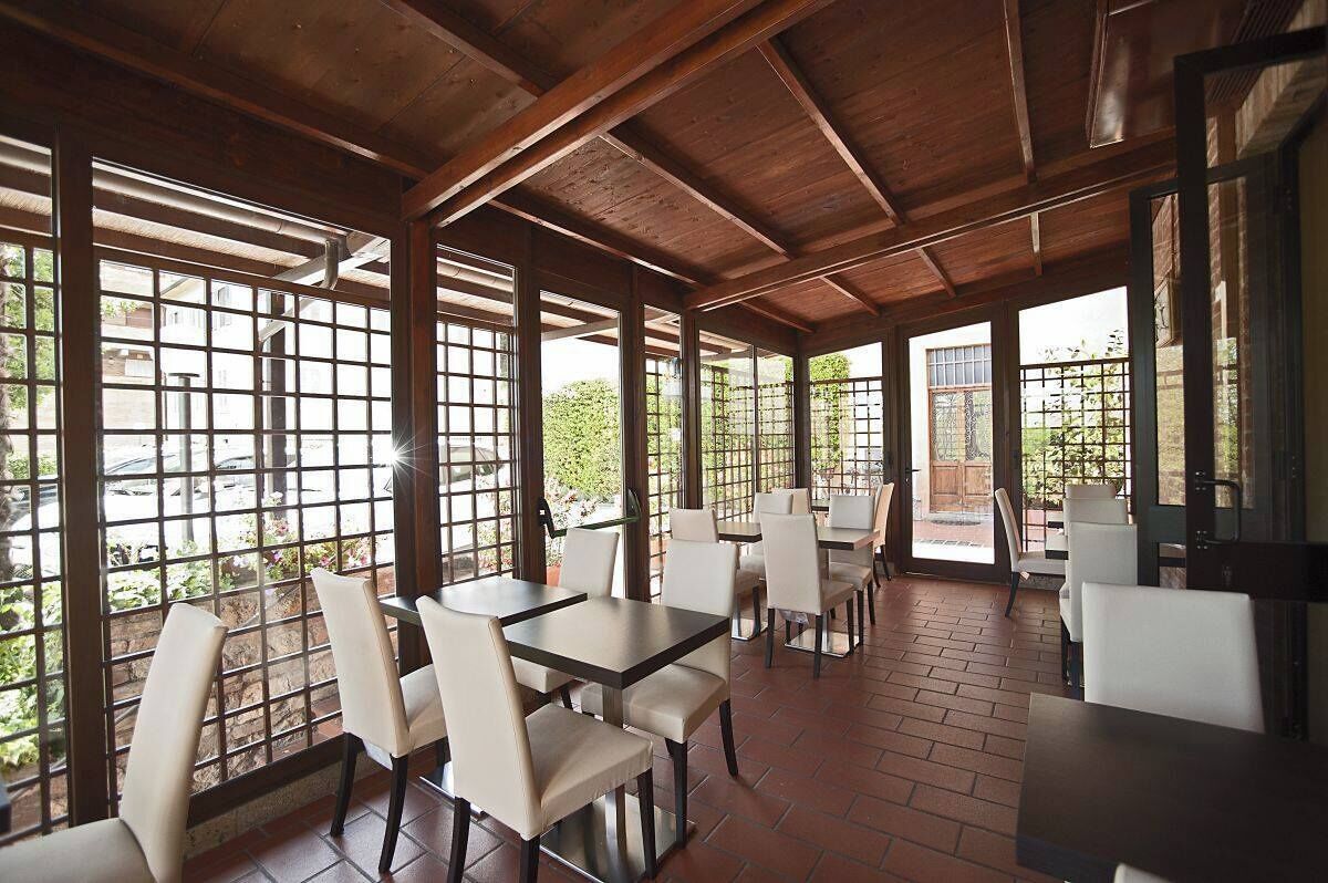 Un restaurante con vigas de madera y ventanas amplias. Mesas y sillas dispuestas para comer.