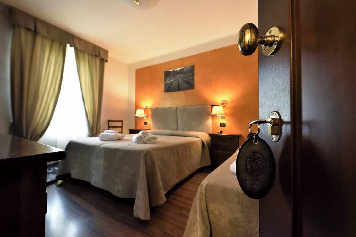 Una habitación de hotel con dos camas, un escritorio y una puerta con cerradura de llave.