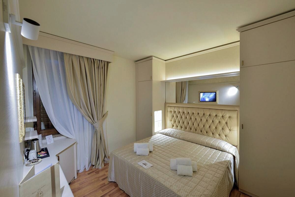 Une chambre d’hôtel avec un lit, un bureau, un miroir et une télévision.