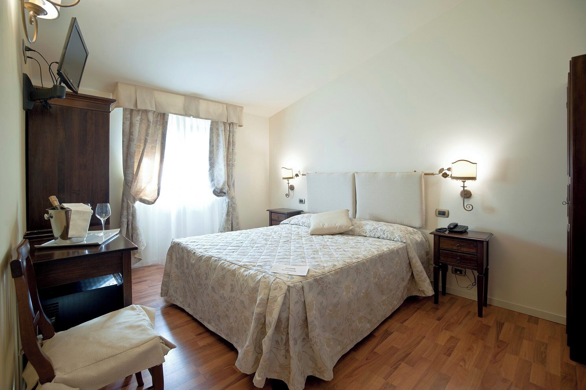 Une chambre à coucher comprenant un lit, des tables de chevet, un bureau avec une chaise et une armoire.