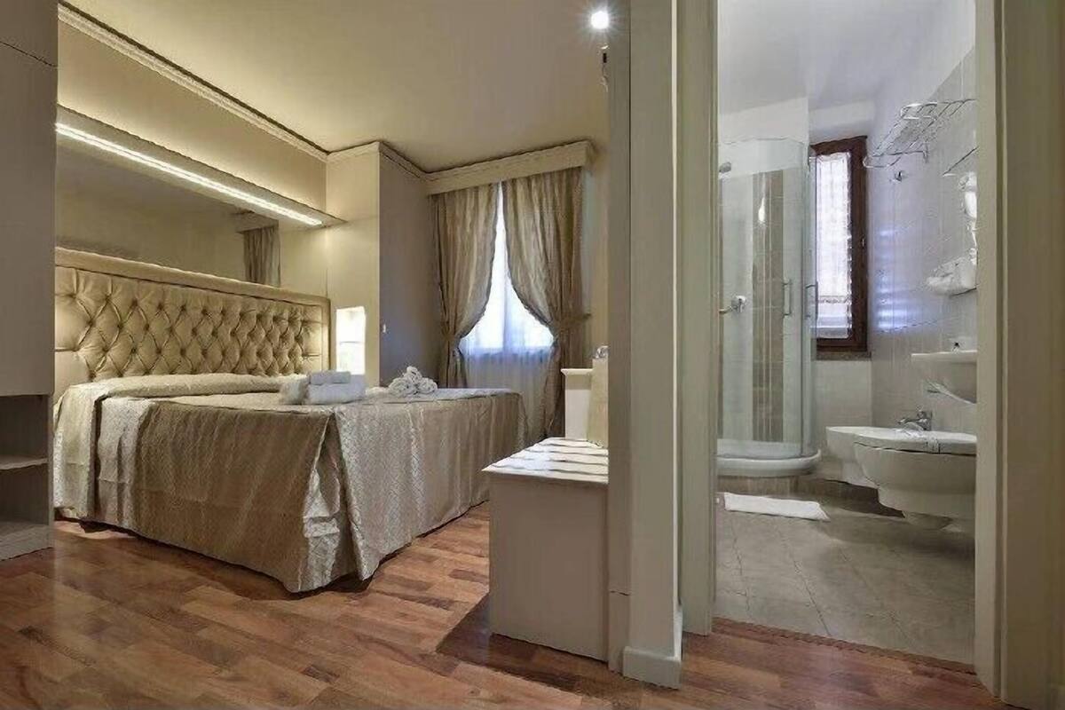 Un dormitorio con una cama grande, una mesita de noche y un baño con ducha y lavabo.