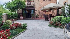 Un patio empedrado con una bicicleta, plantas en macetas y mobiliario de exterior.