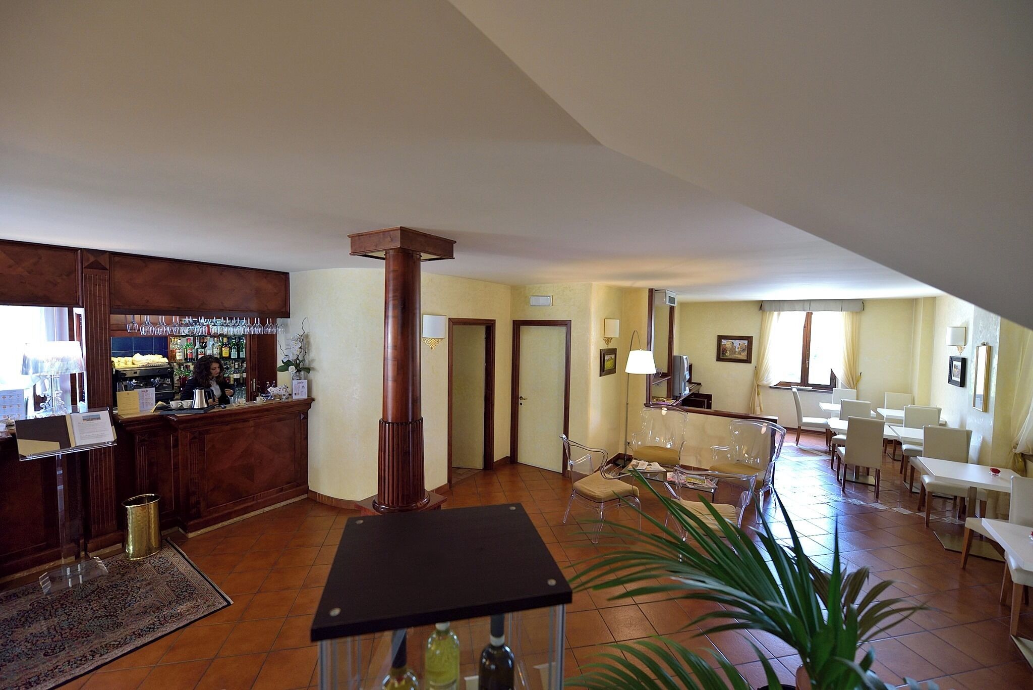 A spacious lobby with a bar area, seating, and a large plant.