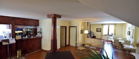 A spacious lobby with a bar area, seating, and a large plant.