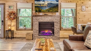 Ein gemütliches Blockhaus-Interieur mit Kamin aus Naturstein, einem großen Fenster mit Seeblick und rustikalem Holzinterieur.