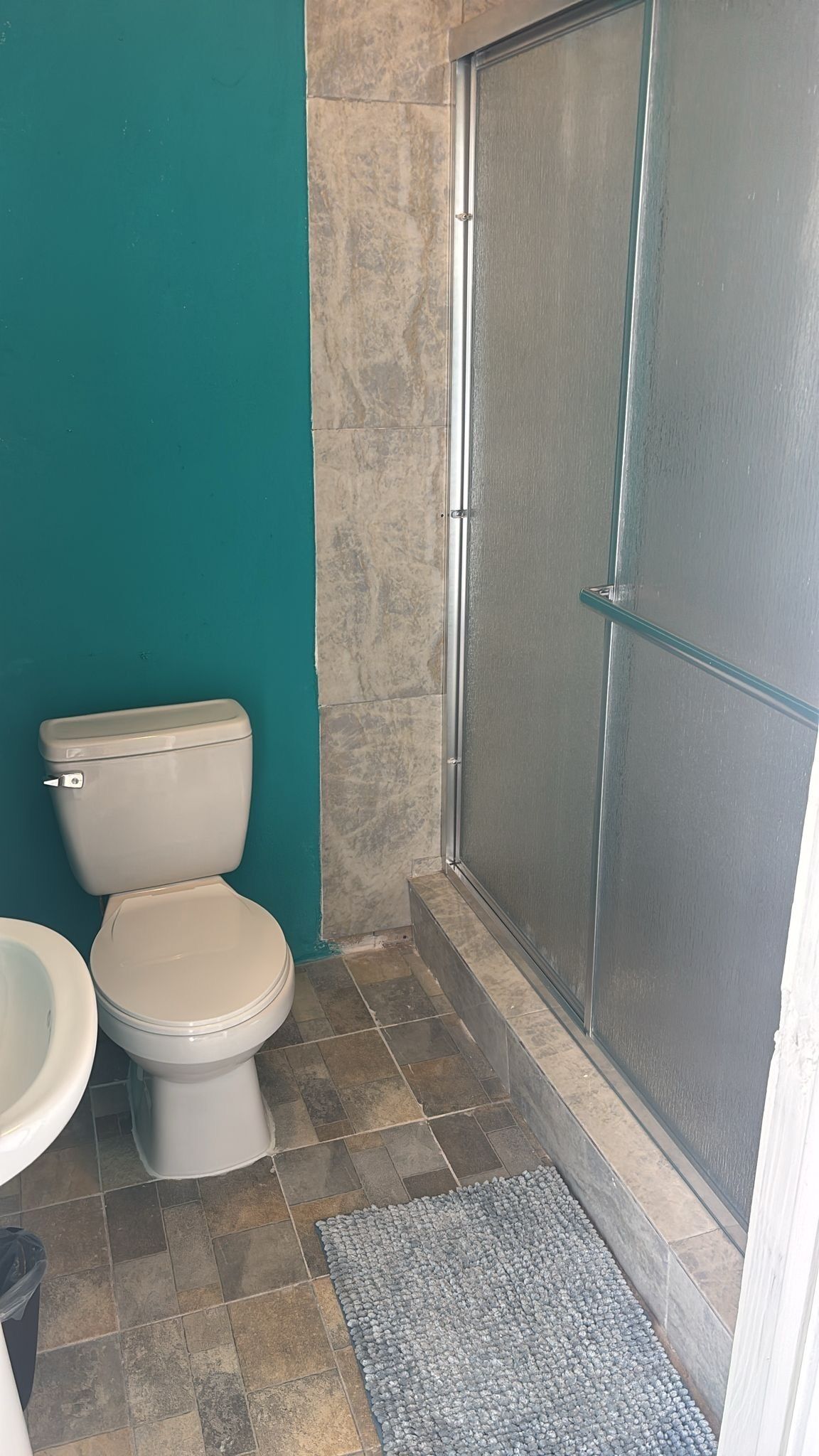 A bathroom with a toilet, a shower enclosure, and a sink.