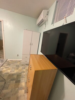 Une pièce avec un meuble en bois, un plan de travail noir et une armoire blanche.