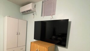 Habitación con armario, televisor de pantalla plana montado en la pared y aire acondicionado.