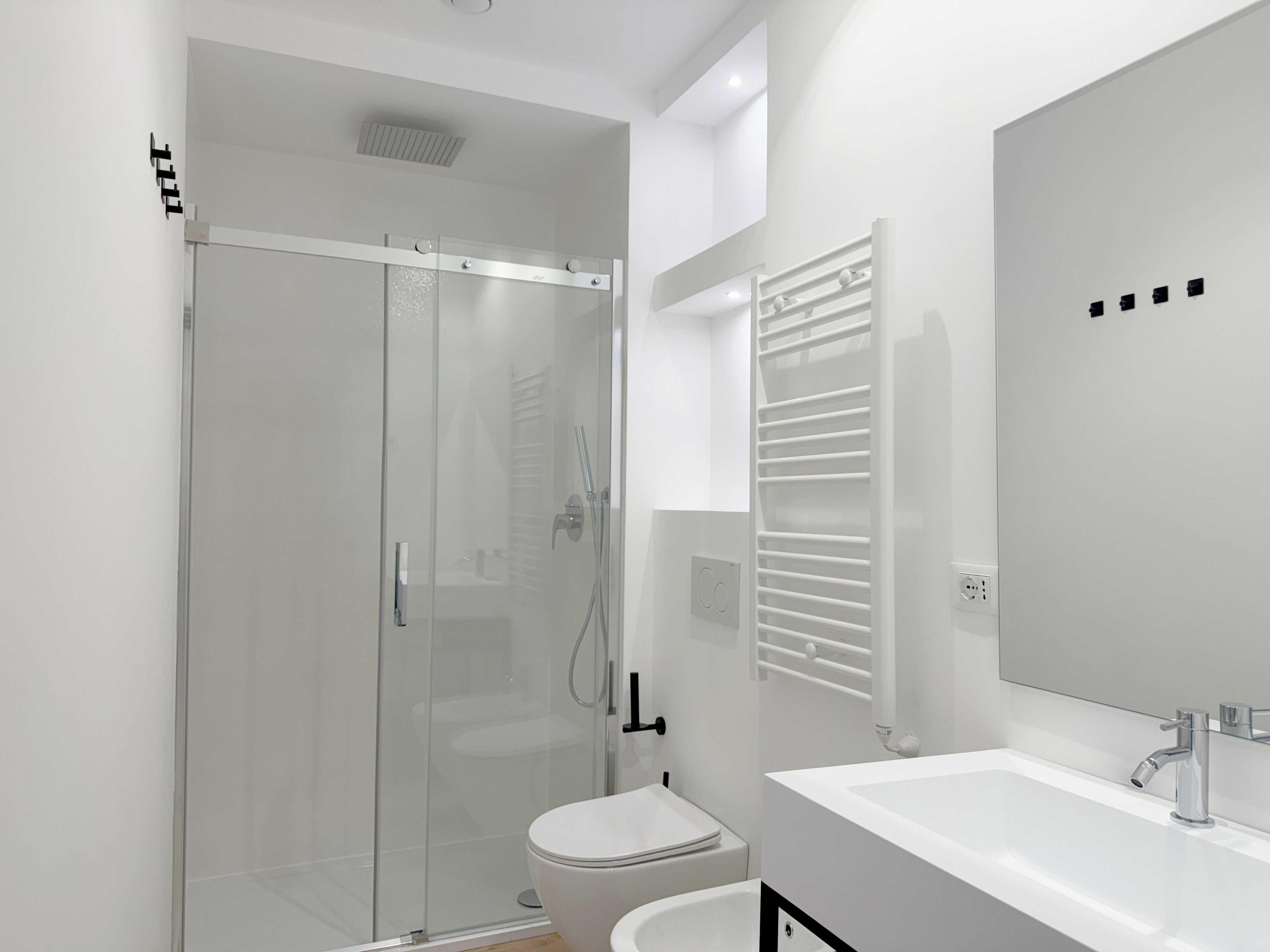 A modern bathroom with a glass shower enclosure, a white toilet, and a white sink with a mirror above it.