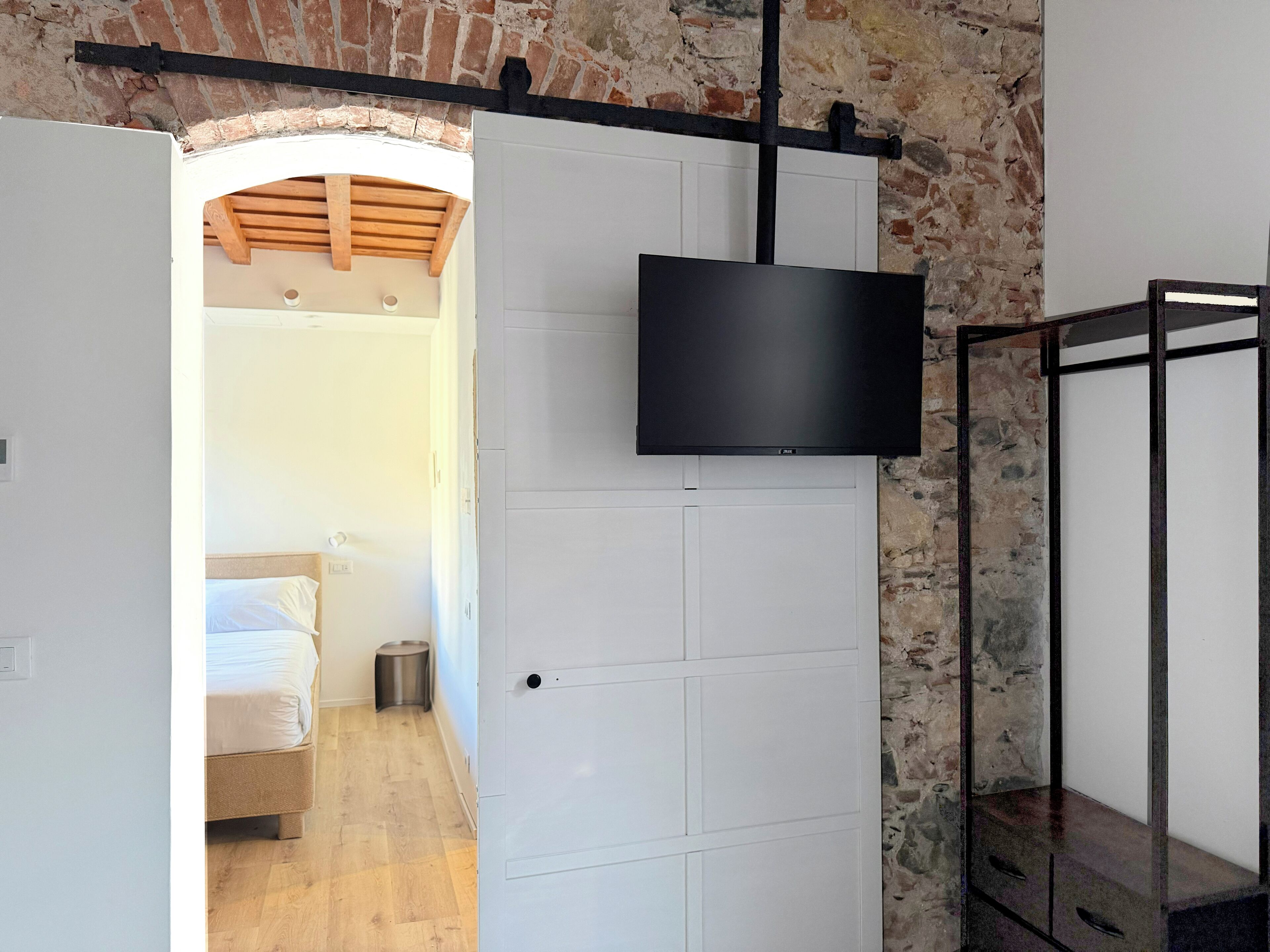 Una camera moderna con soffitto in legno, una porta bianca e una TV a parete.