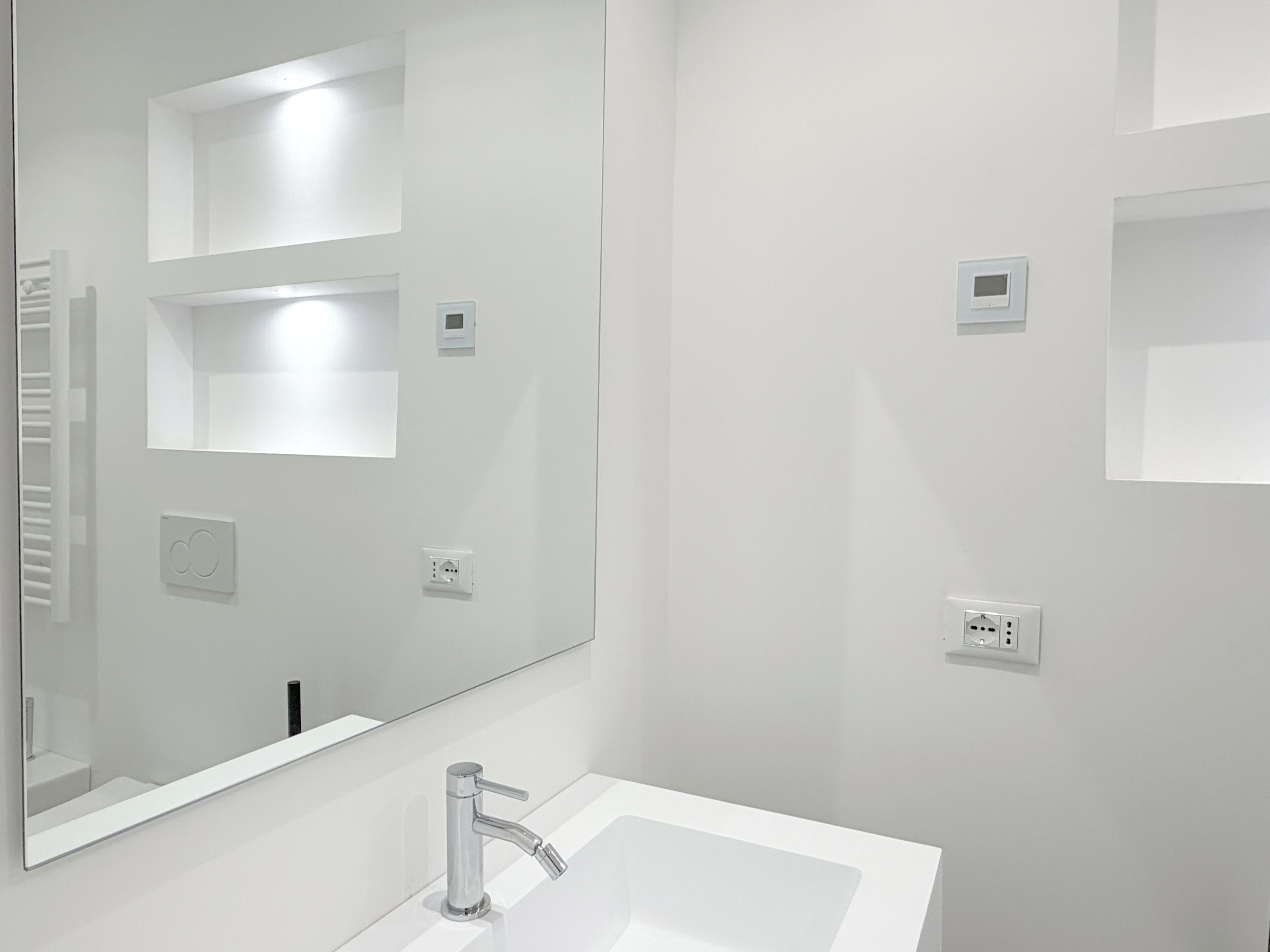 Une salle de bain moderne avec un grand miroir, un lavabo et des toilettes.