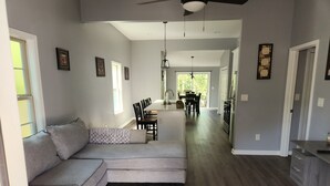 A modern living room with a gray sectional sofa, a dining area with a wooden table and chairs, and a kitchen with dark wood flooring. - 3-bedroom house in fantastic Atlanta with cool AC and comfort close to downtown (Atlanta)