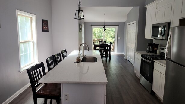 A modern kitchen with a central island, white cabinetry, and stainless steel appliances. - 3-bedroom house in fantastic Atlanta with cool AC and comfort close to downtown (Atlanta)
