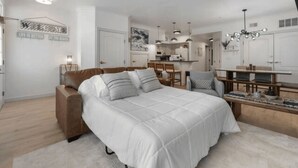 A modern bedroom with a large bed, a desk, and a kitchenette. - The Lakeside Duo | Side-By-Side Beachfront Condos (Sheboygan)