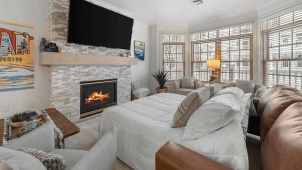 A cozy living room with a fireplace, comfortable seating, and large windows. - The Lakeside Duo | Side-By-Side Beachfront Condos (Sheboygan)
