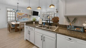 A modern kitchen with granite countertops, white cabinetry, and pendant lighting. - The Lakeside Duo | Side-By-Side Beachfront Condos (Sheboygan)