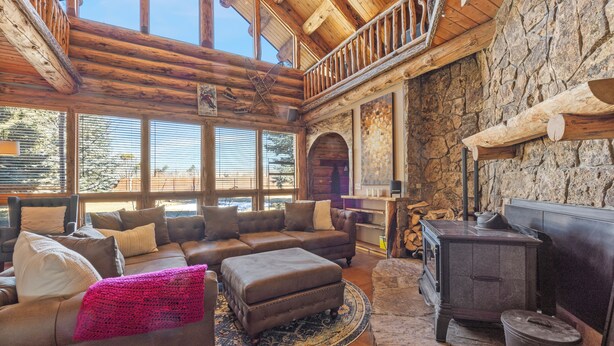 A cozy living room with a large sectional sofa, a fireplace, and a stone wall. - Rustic-Luxury Mountain Retreat Close to Montrose, Ouray, and Telluride (Montrose)