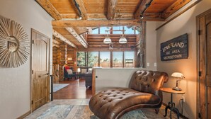A spacious living area with a leather sofa, a wooden coffee table, and a large mirror. A sign on the wall reads "Love Land Sky Area Georgetown." - Rustic-Luxury Mountain Retreat Close to Montrose, Ouray, and Telluride (Montrose)