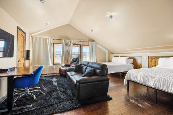 A modern bedroom with a sloped ceiling, a desk with a chair, a sofa, and a bed. - Rustic-Luxury Mountain Retreat Close to Montrose, Ouray, and Telluride (Montrose)