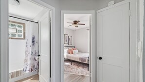 Ein Schlafzimmer mit Bett, Deckenventilator und einem Fenster mit Vorhang.