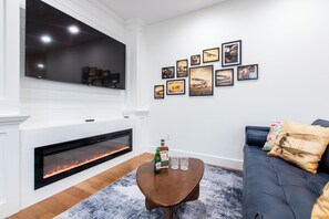 Een moderne woonkamer met een open haard, een flatscreen televisie en een muur versierd met luchtvaartkunst.