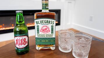 Una bottiglia di whiskey bourbon Bluegrass Kentucky Straight e una bottiglia di Ales 8.1 su un tavolo di legno, con due bicchierini.