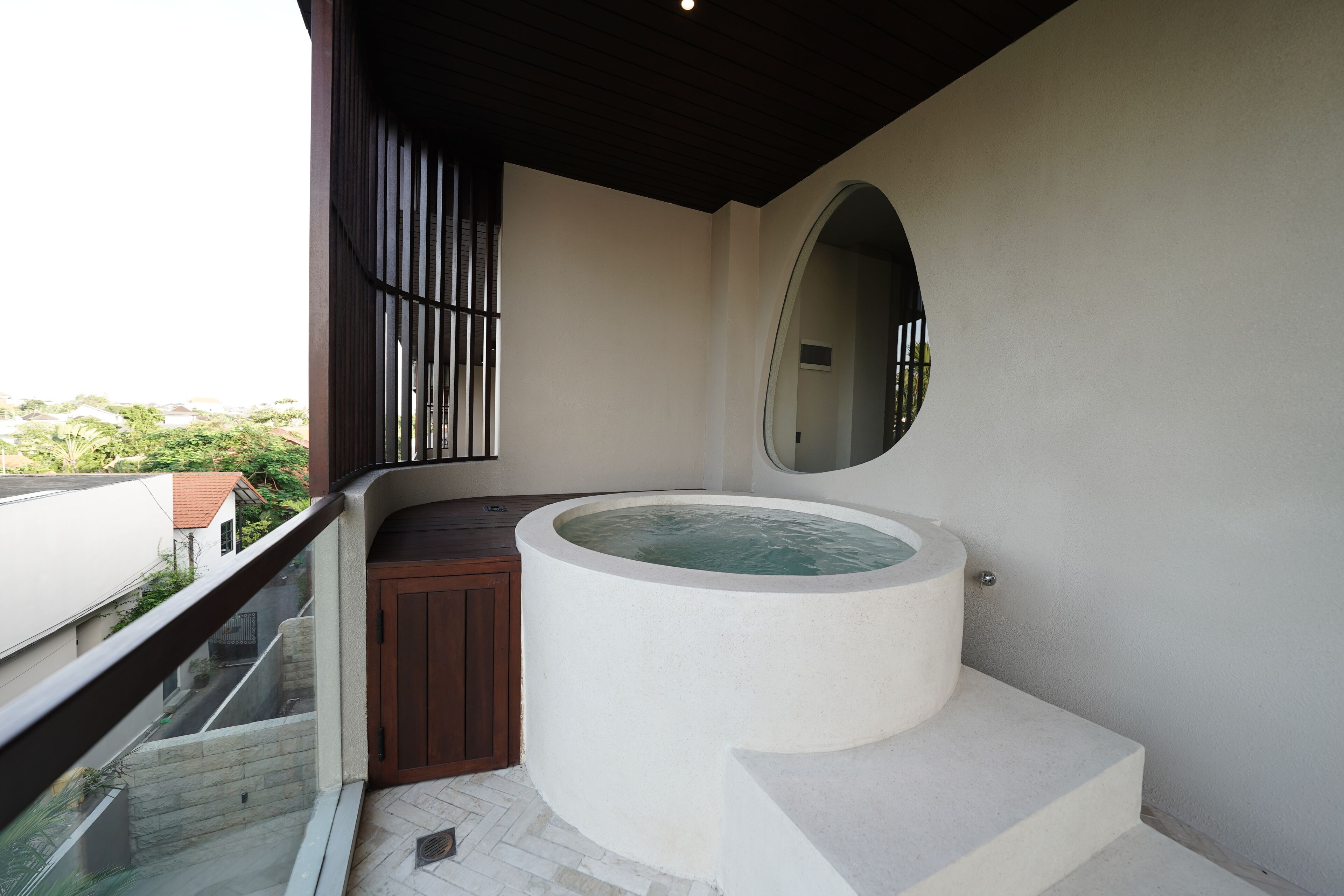A modern bathroom with a large bathtub, a wooden cabinet, and a large mirror.