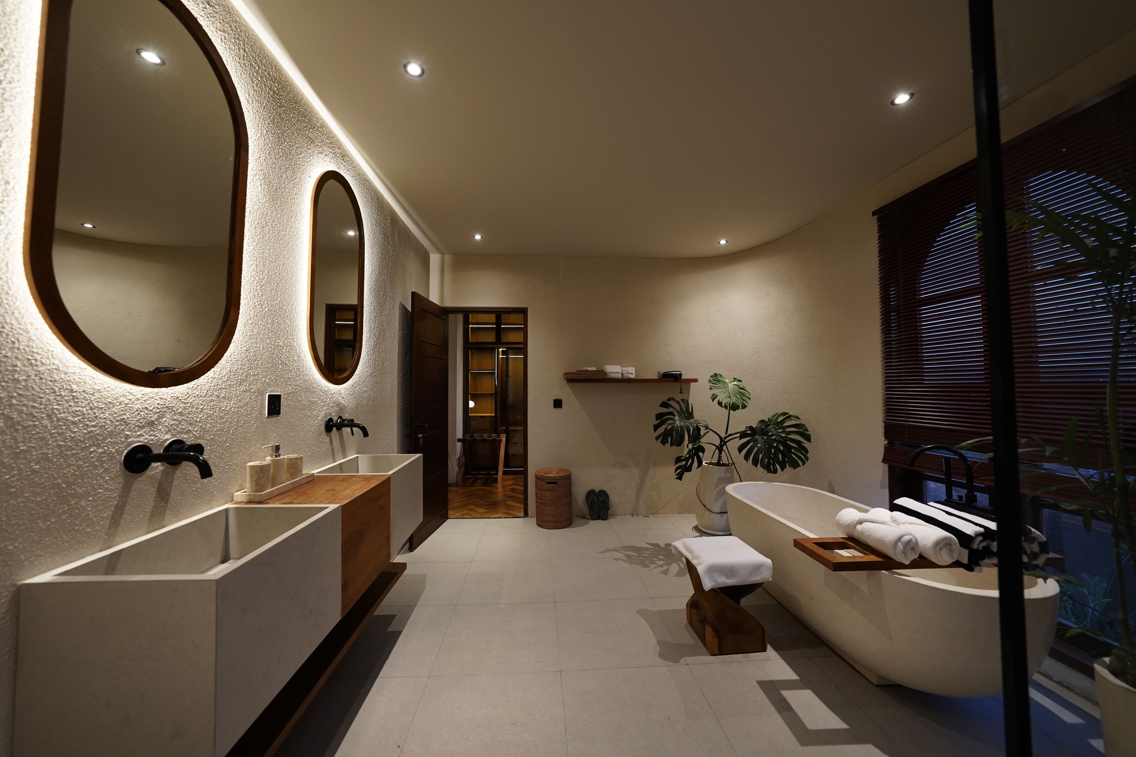 Un baño moderno con dos lavamanos, una bañera y un espejo grande.