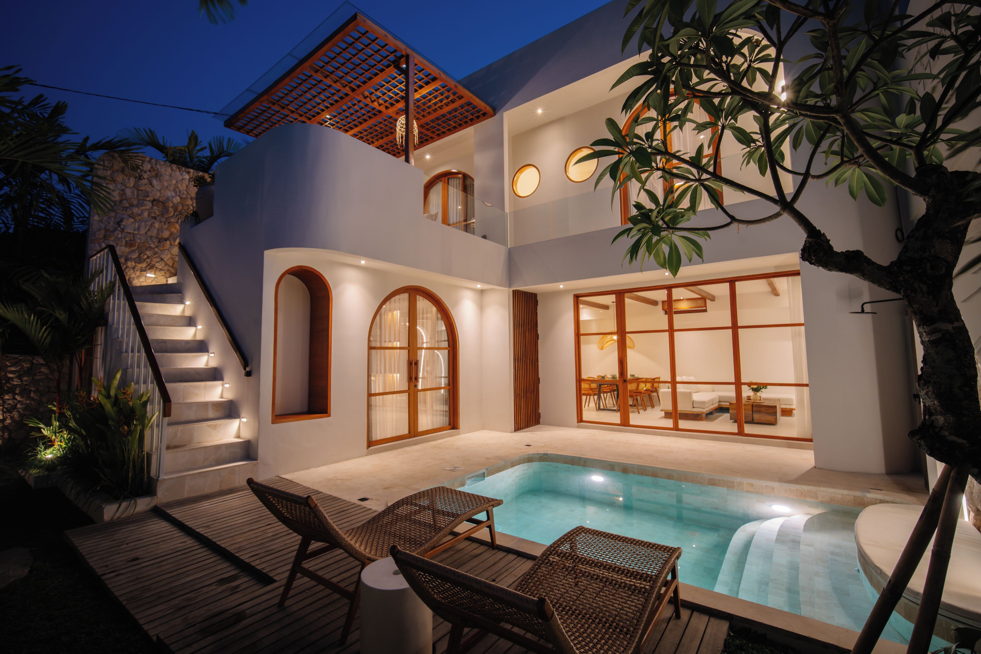 A modern house with a swimming pool, wooden deck, and outdoor seating.