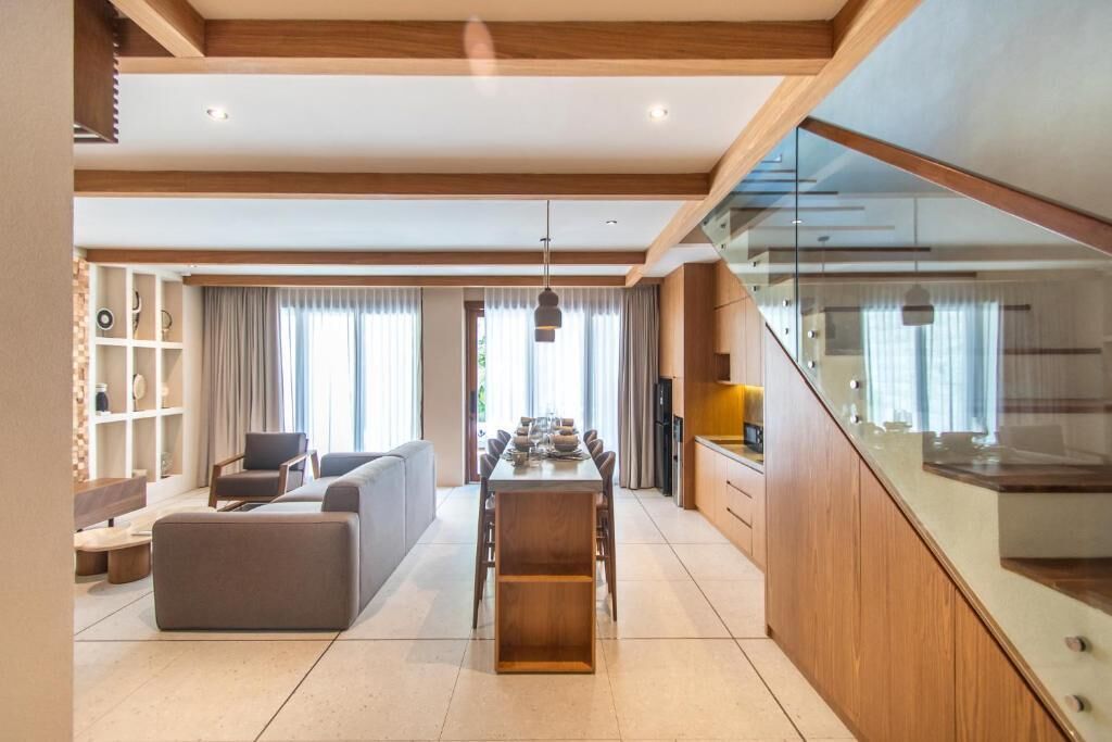 A spacious living area with a dining table, sofa, and kitchen in the background.