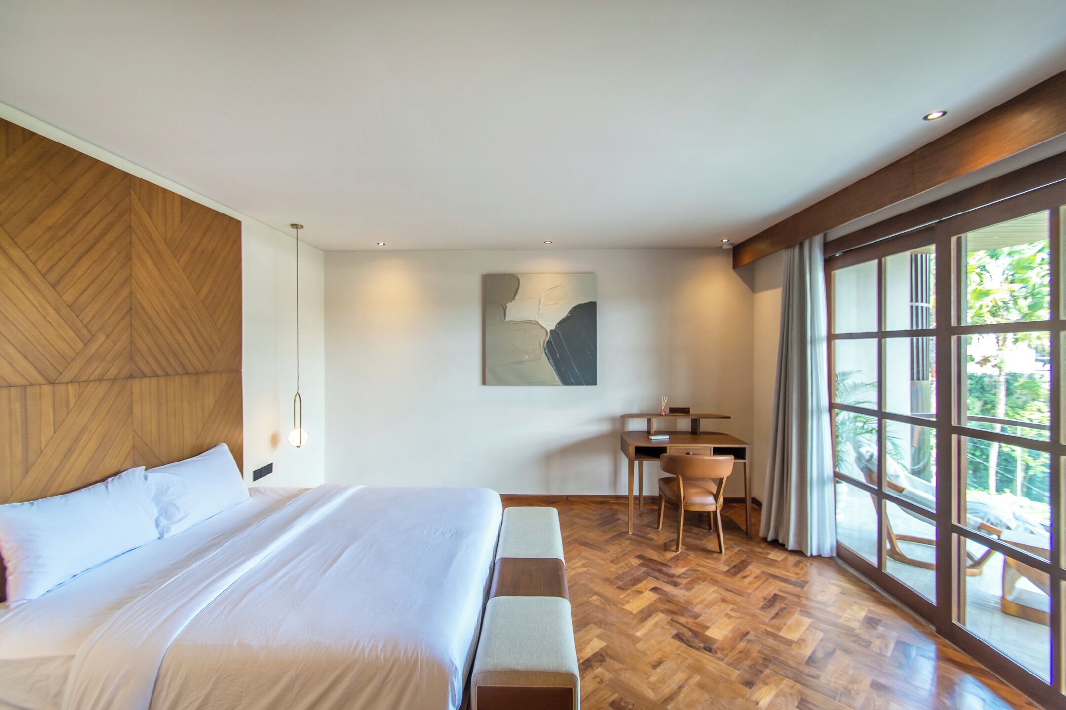 Una habitación de hotel moderna con una cama grande, un escritorio y vistas amplias a través de grandes ventanales.
