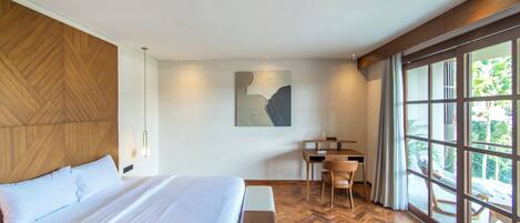 Una habitación de hotel moderna con una cama grande, un escritorio y vistas amplias a través de grandes ventanales.