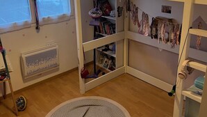 Lastenhuone, jossa on kerrossänky, patteri, huurretta sisältävä ikkuna, riippuvalaisin ja kirjahylly.