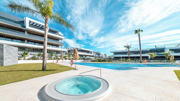 Un hotel moderno con piscina, palmeras y jacuzzi.