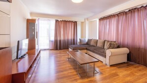A modern living room with a sofa, a coffee table, and a flat-screen TV on a wooden stand. - AMBER apartments Spacious FLAT near park SIBIU #28 (Sibiu)