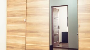 A wooden wardrobe with a mirrored door, a visible door handle, and a light switch on the wall. - AMBER apartments Spacious FLAT near park SIBIU #28 (Sibiu)