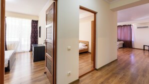 A spacious room with a wooden floor, a bed, a desk, and a chair. - AMBER apartments Spacious FLAT near park SIBIU #28 (Sibiu)