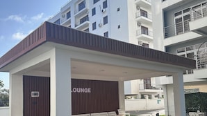 A modern lounge area with white chairs and a sign that reads "KEEP OFF THE GRASS".